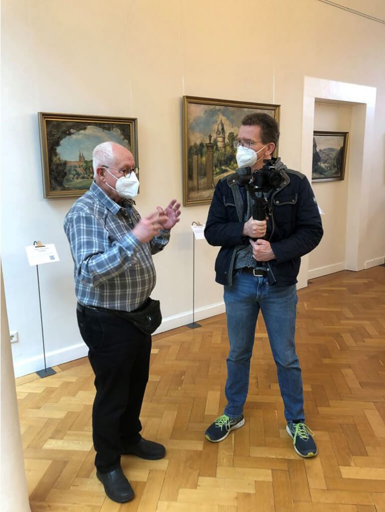 Der ehemalige Vorsitzende des Lippischen Künstlerbundes Günter Schulz (links) erläutert WDR-Reporter Markus Rinke (rechts) die spannenden Entwicklungen rund um die Maler in Lippe.